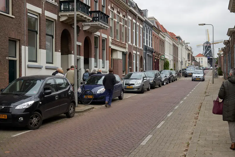 Woonstraat in Klarendal met bakstenen gevels, geparkeerde auto's en de molen De Kroon in de verte