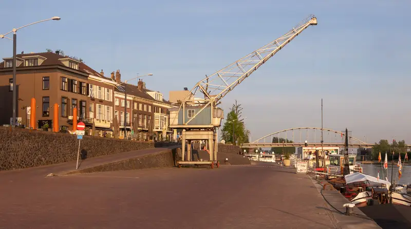 Rijnkade in Arnhem bij avondlicht, met de historische havenkraan en de gevels langs de kade