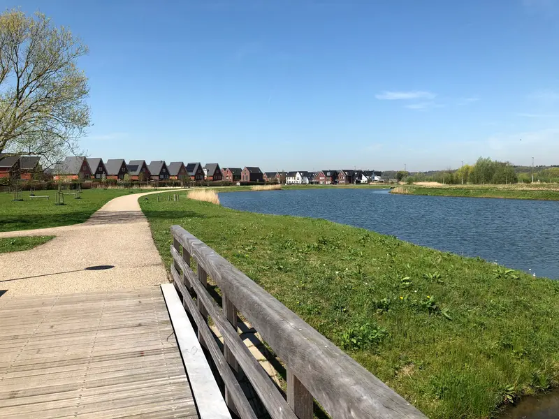 Nieuwbouwwoningen aan een waterpartij in Schuytgraaf, met een houten vlonderpad op de voorgrond
