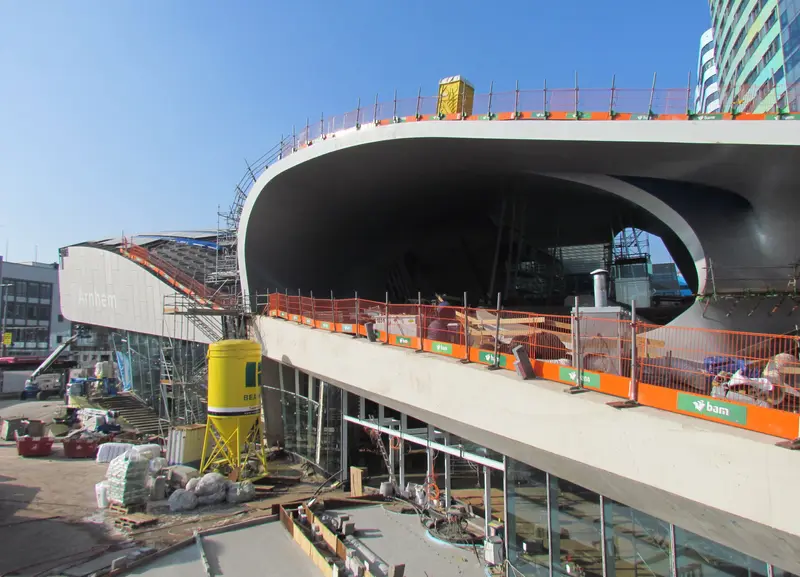 Bouwplaats van de nieuwe stationshal van Arnhem Centraal met steigers, bouwhekken en materiaal